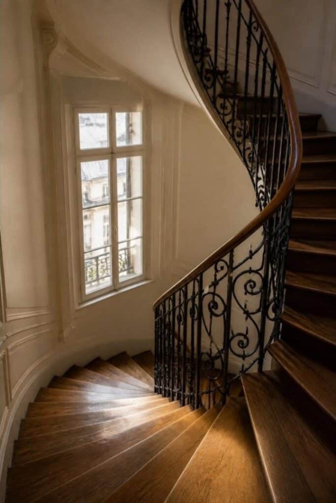 Cage d'escalier d'immeuble parisien avec rampe en fer forgé